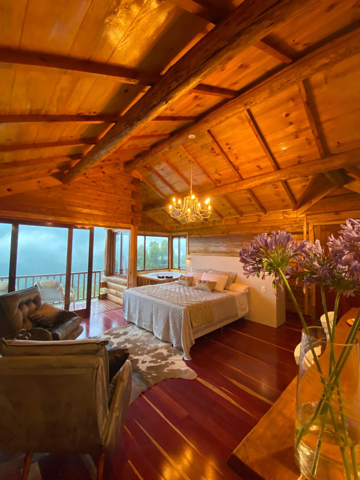 Interior em madeira com cama e janelas para a serra